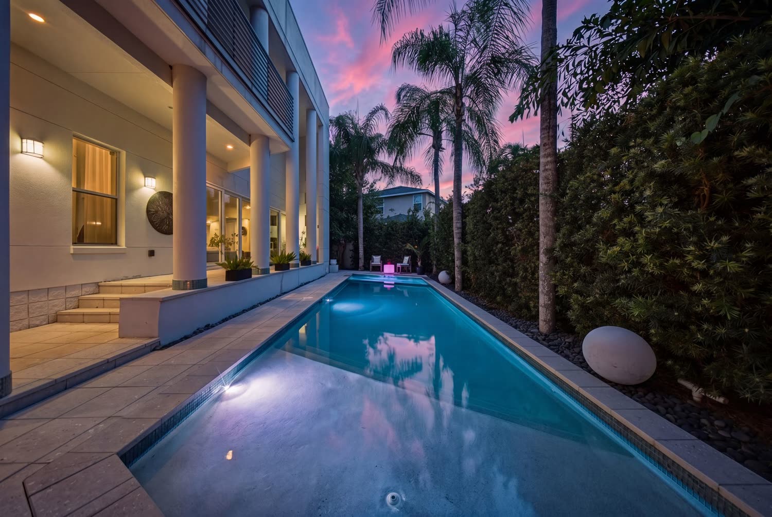 Twilight real estate photograph of a Tampa pool and lanai at sunset with the house lit from inside