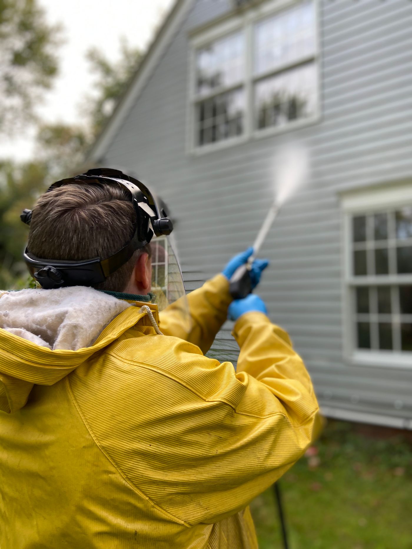 Technician soft washing the siding of a two story home